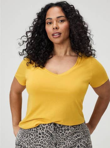 Person wearing a V-neck T-shirt and leopard-print pants, posing confidently