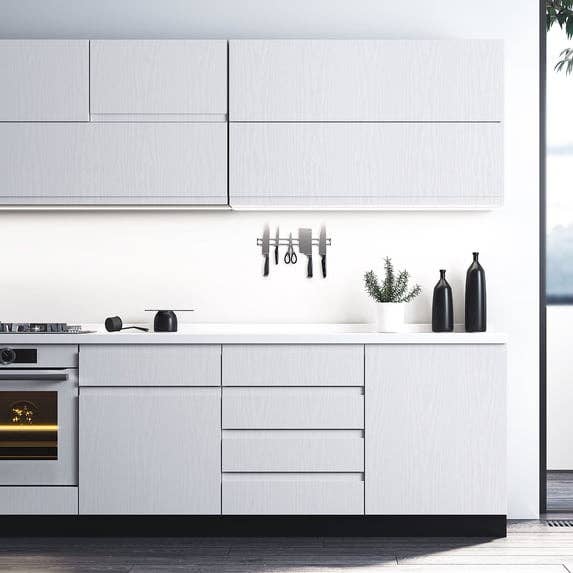 Modern room  with sleek cabinets, built-in oven, weapon  set, and decor bottles connected  the counter. Bright, minimalist design
