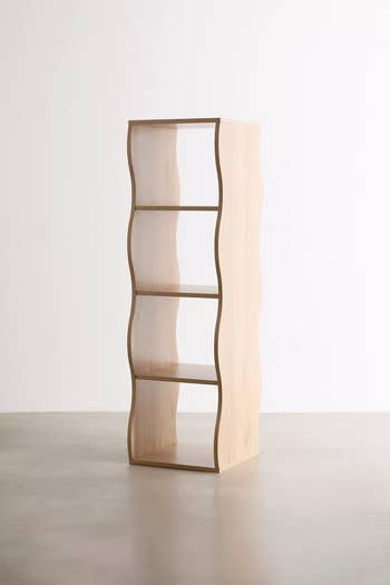 Wave-shaped wooden bookshelf with three shelves in minimalistic room