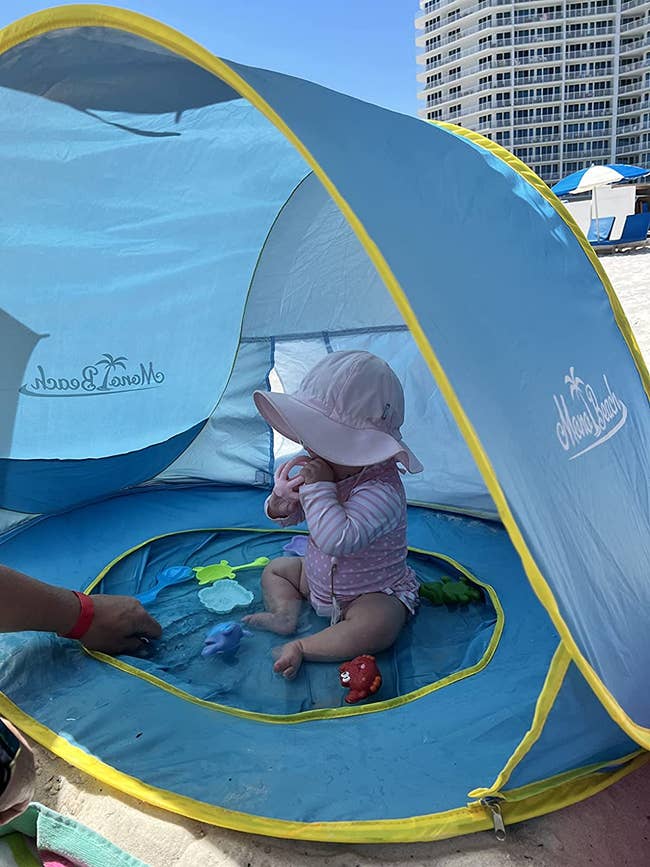 a baby sitting in a pop up tent in a pool