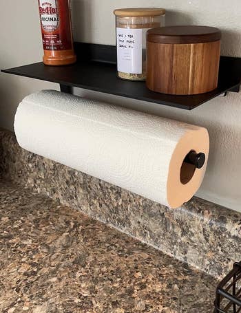another reviewer's matte black paper towel holder holding towels as well as spices and candles on top