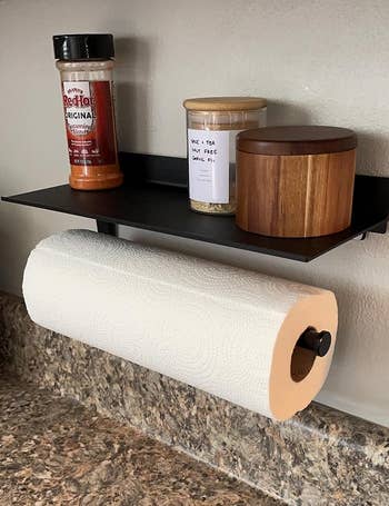 another reviewer's matte black paper towel holder holding towels as well as spices and candles on top