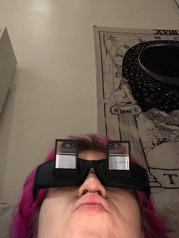 a reviewer wearing the glasses to show how they help you view things while lying down