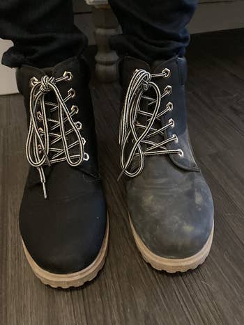 reviewer wearing one clean lace- up boot after using the shoe cleaner and one dirty boot before using it 
