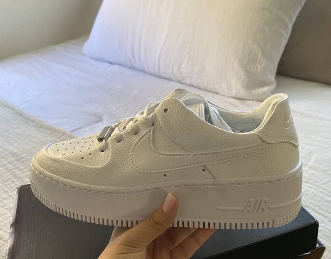 reviewer hand holding the white platform sneakers