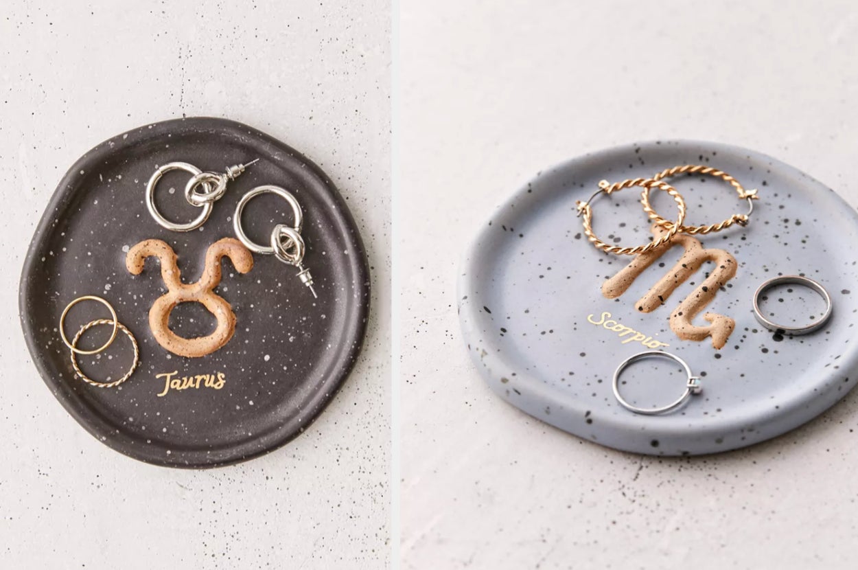 Black jewelry tray with Taurus symbol and rings and earrings on it, product in gray with black speckles and the Scorpio symbol in gold with jewelry