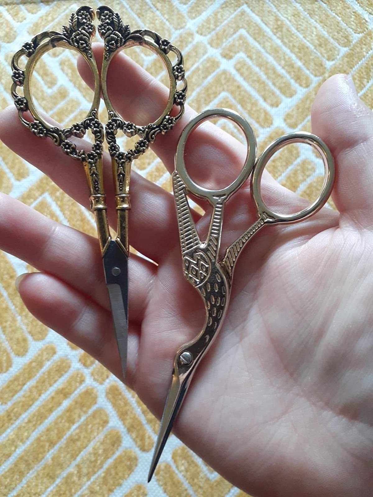 reviewer's hand holding both sets of gold scissors