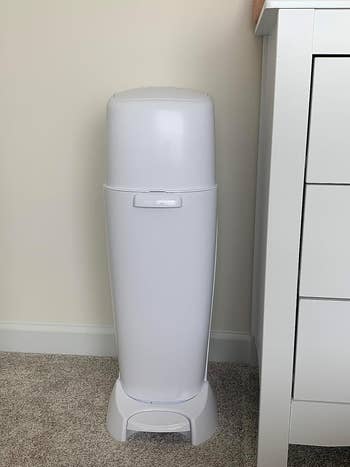 Diaper disposal bin adjacent to a dresser successful a nursery