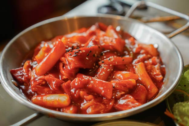 Ein Gericht aus Tteokbokki, koreanischen gebratenen Reiskuchen, in scharfer Soße, garniert mit Sesamkörnern in einer Pfanne