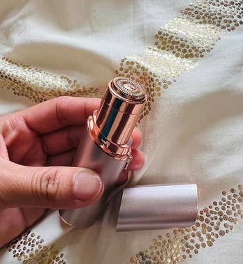 A hand holding a stylish lipstick over a fabric with golden sequin details. Perfect for makeup enthusiasts