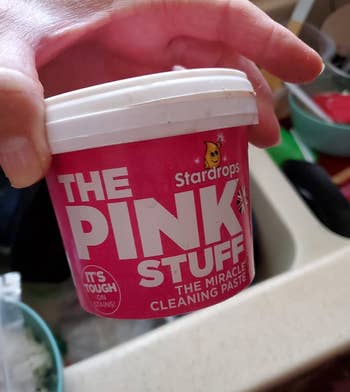 Reviewer holding up the small pink container 