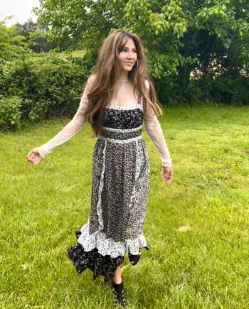 Person outdoors successful  a flowy floral formal  with layered textures and lace sleeves, walking connected  writer  surrounded by greenery