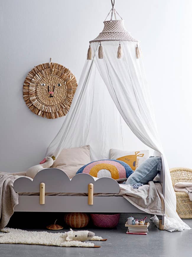 canopy with lampshade-like macrame top hanging over a bed 