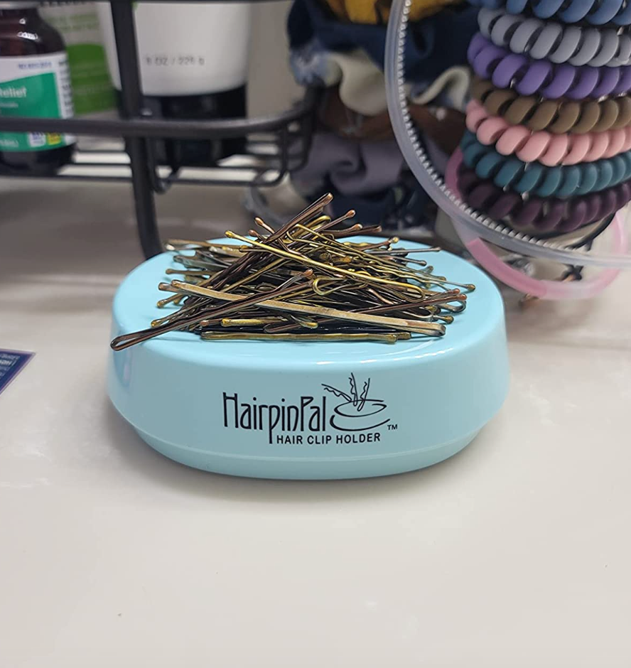 A blue oval shaped magnet with dozens of bobby pins stacked on top 