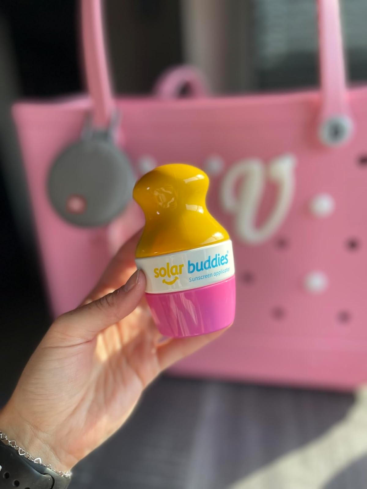 reviewer holding the pinkish  sunscreen applicator