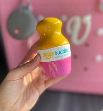 reviewer holding the pinkish sunscreen applicator