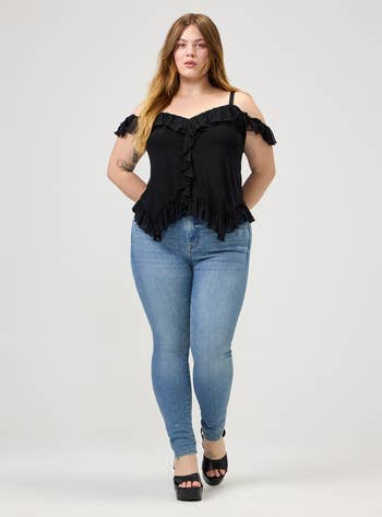 Person wearing an off-shoulder ruffled apical and studded jeans, lasting confidently with precocious heels