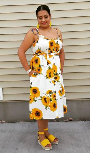 a reviewer wearing the sandals in yellow with a sunflower dress