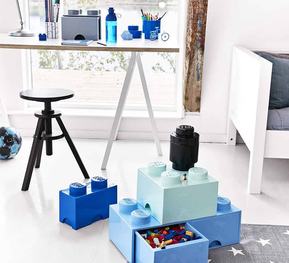 Oversized LEGO-inspired storage boxes in a playroom with scattered toy bricks on the floor