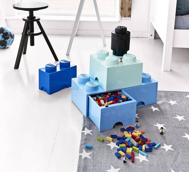 Oversized LEGO-inspired storage boxes in a playroom with scattered toy bricks on the floor