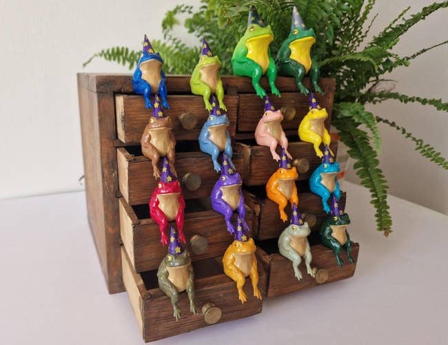 Small drawers adorned with colorful frog figures wearing wizard hats, evoking a whimsical decor style