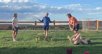 People playing a game with yellow tubes and a ball on a grassy field, casual outdoor attire, relaxed atmosphere