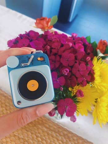 a reviewer holds the bluish  speaker