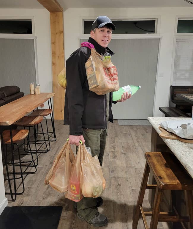 reviewer using the grocery bag carrier to carry multiple bags