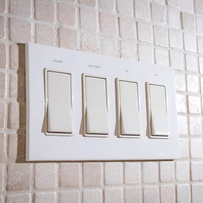 four switch plate with engraved words: shower, main lights, tub, and sink above switches