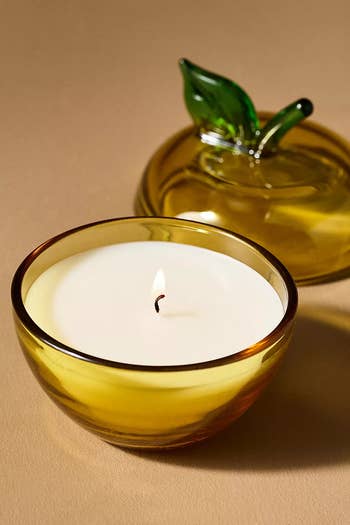 Glass apple-shaped candle holder with lid beside an unlit candle inside, suitable for location decor oregon gifting
