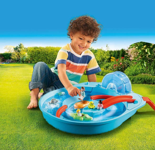 Child playing with blue and red plastic Playmobil toy with figures 