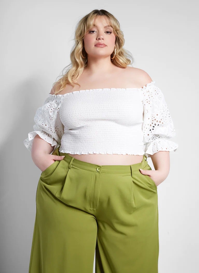 a plus size model wearing the smocked peasant top with green pants