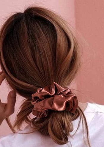 back of model wearing a rust colored satin scrunchie in their hair