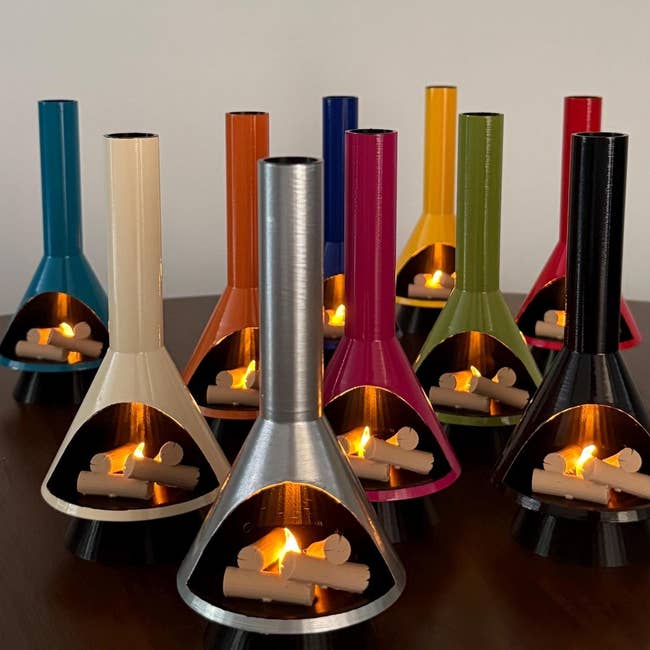 Miniature cone-shaped fireplaces with metallic chimneys and tiny logs inside, disposable successful assorted colors, displayed connected a table