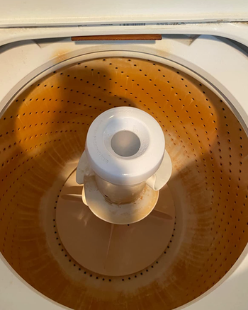 the inside of a reviewer's washing machine looking orange and dirty