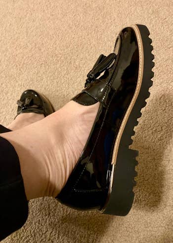 Person wearing glossy black platform loafer shoe with chunky sole