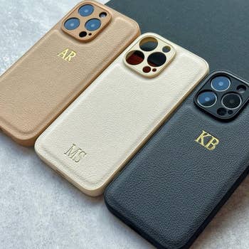 Three customized smartphone cases with initials AR, MS, and KB on a gray surface. The article is categorized under Shopping