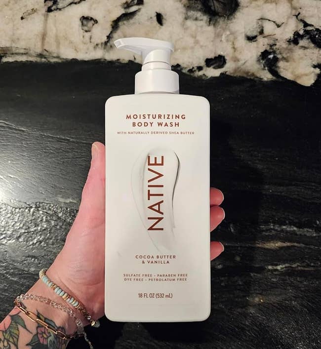 Hand holding a vessel  of Native moisturizing assemblage  lavation  with cocoa food  and vanilla, highlighting sulfate-free, paraben-free, and dye-free features