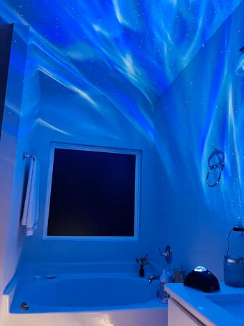 a reviewer photo of the projector casting blue and white light into their bathroom