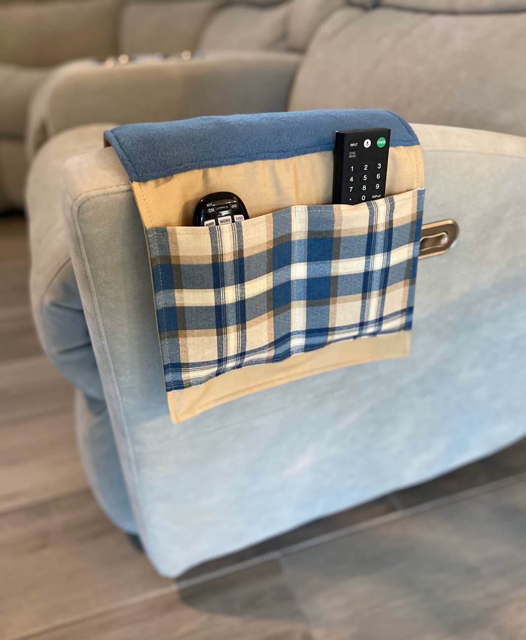 the tan and blue couch caddy with remotes inside of it 