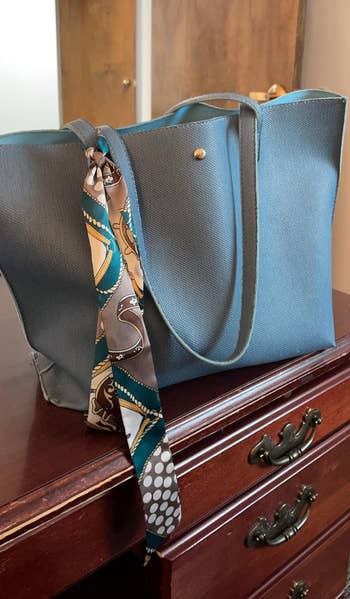 Elegant tote container connected a woody dresser, accented with a patterned scarf