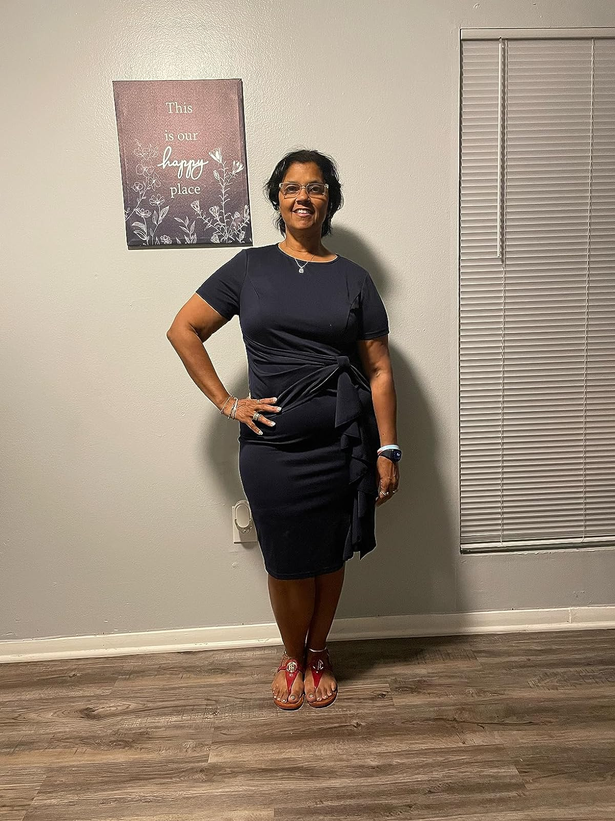 Reviewer standing in a room wearing a stylish navy dress and red sandals