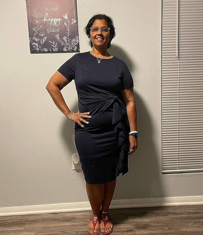 Reviewer standing in a room wearing a stylish navy dress and red sandals