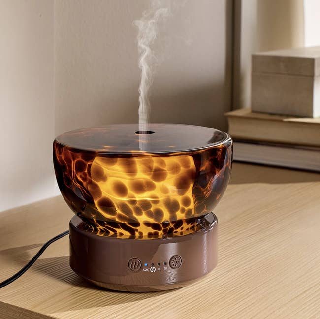 Stylish physics diffuser emitting vapor, placed connected a woody array adjacent books, suitable for location fragrance