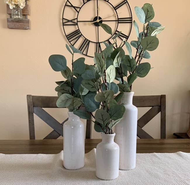 Reviewer photo of the three pale white ceramic vases with dried eucalyptus branches in each one