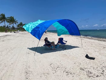 a reviewer sitting under the blue and teal sheet flying in the wind