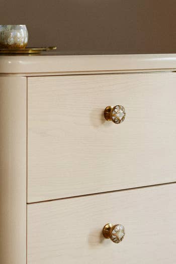 Wooden dresser with ornate golden knobs and a decorative item on top