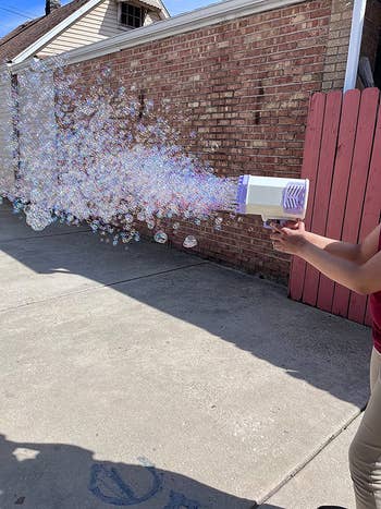 reviewer using bubble gun with lots of bubbles shooting out