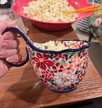Popcorn being served from a colorful floral bowl with a handle