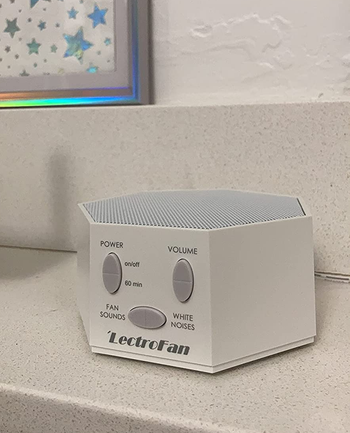 reviewer photo of the white noise machine on a ledge near star-printed artwork